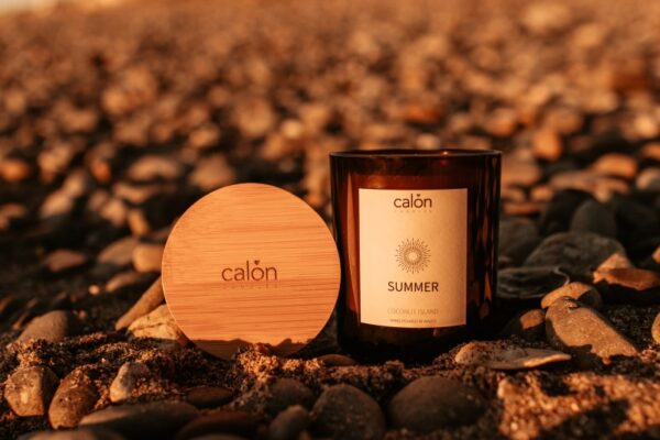 Coconut Island summer candle with branded Calon lid on beach